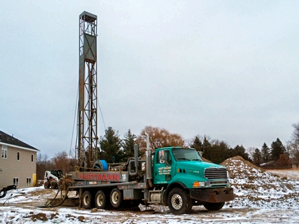Hartmann Well drilling rig drilling a well at a new home construction site
